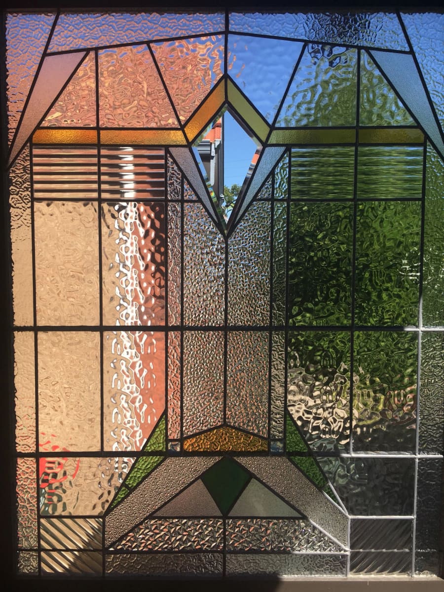 Art Deco leadlight panel of stepped geometric forms in amber, green and blue, backlit