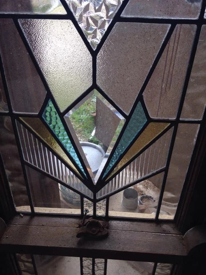 Art Deco transom of a symmetrical amber and teal fan, backlit by the sun