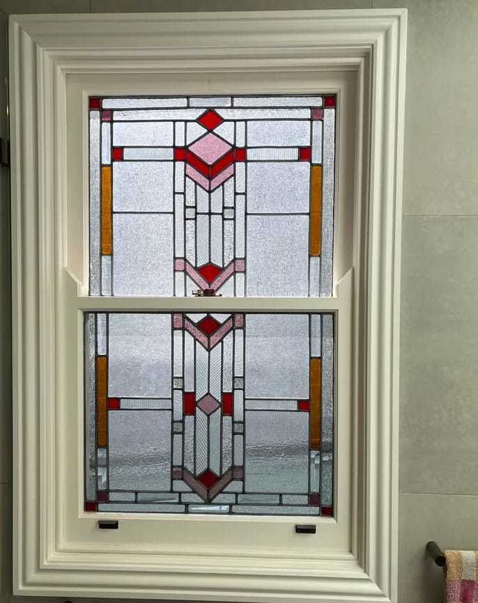 Art Deco leadlight in a restored double-hung window, a stepped red-and-amber fountain motif in each sash