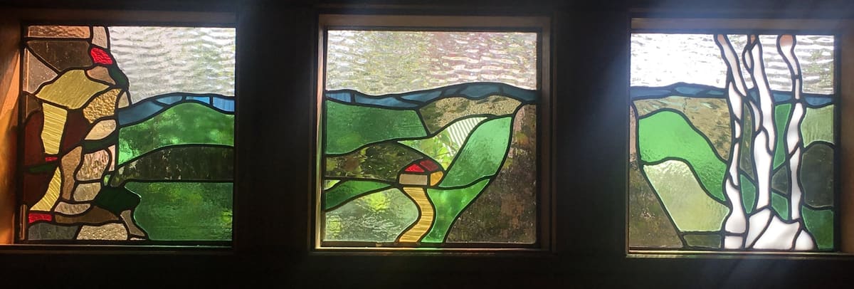 Three-panel Australian native window set installed in a Wentworth Falls home, gum leaves against a green horizon