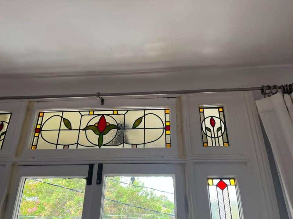 Art Deco door transom with a rose medallion motif in red and gold, above French doors