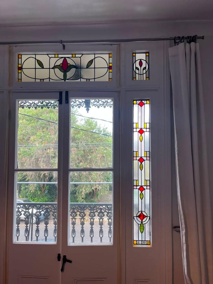 Art Deco French doors installed with matching rose-medallion sidelights, balcony visible through the glass
