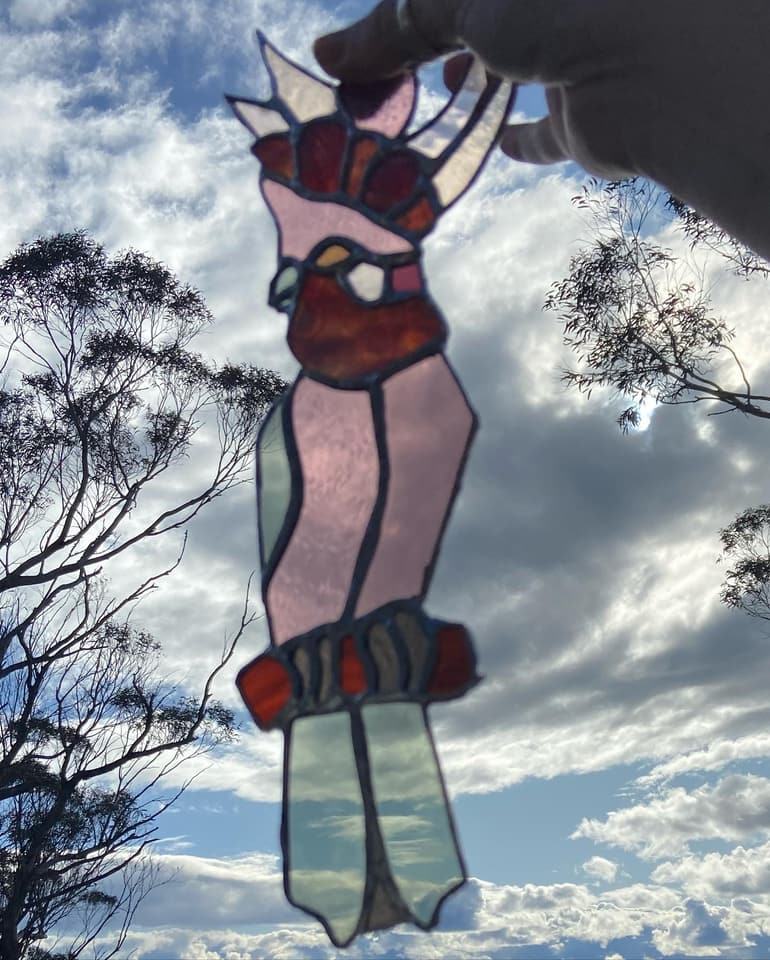 Native bird in leadlight silhouetted against sky and gum trees