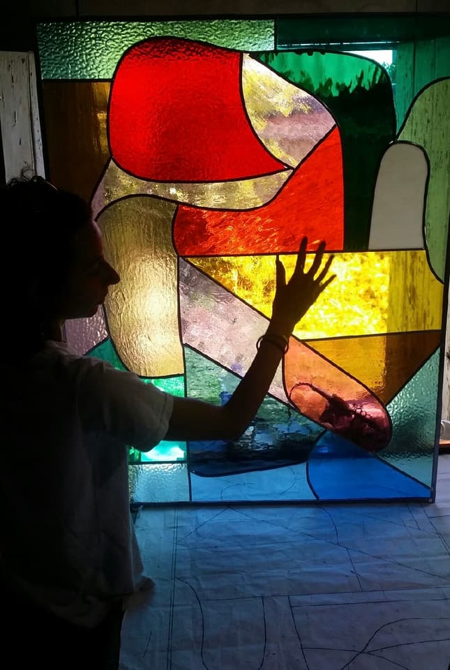 Kirby silhouetted against a large abstract modern leadlight panel