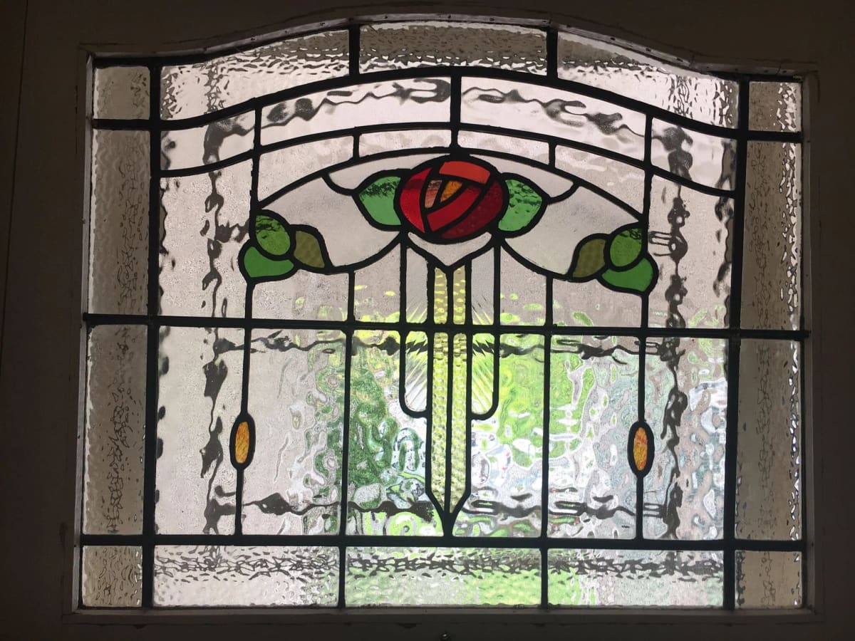 Federation fanlight with a central red rose and green leaves in an arched clear-textured surround
